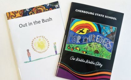 Two Indigenous story books fanned out on a white desktop. One is titled Out in the Bush, the other is For Our Elders.